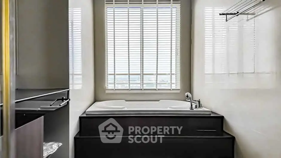 Luxurious bathroom with a modern bathtub and large window with blinds.