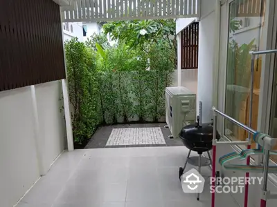 Charming small garden patio with lush greenery and modern outdoor grill