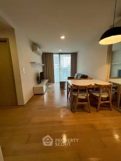 Modern living room with wooden flooring, cozy seating, and dining area in open layout apartment.