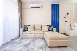 Modern living room with stylish beige sofa and air conditioning, featuring elegant decor and natural light.