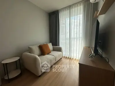 Cozy living room with modern sofa and large window, perfect for relaxation.