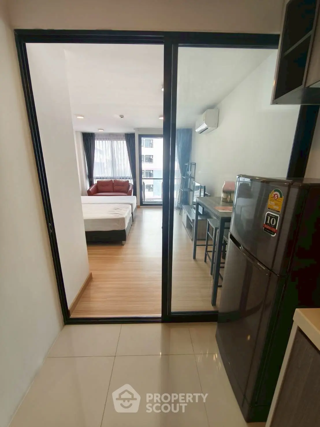 Modern apartment interior with open layout, featuring a cozy living area and sleek kitchen appliances.