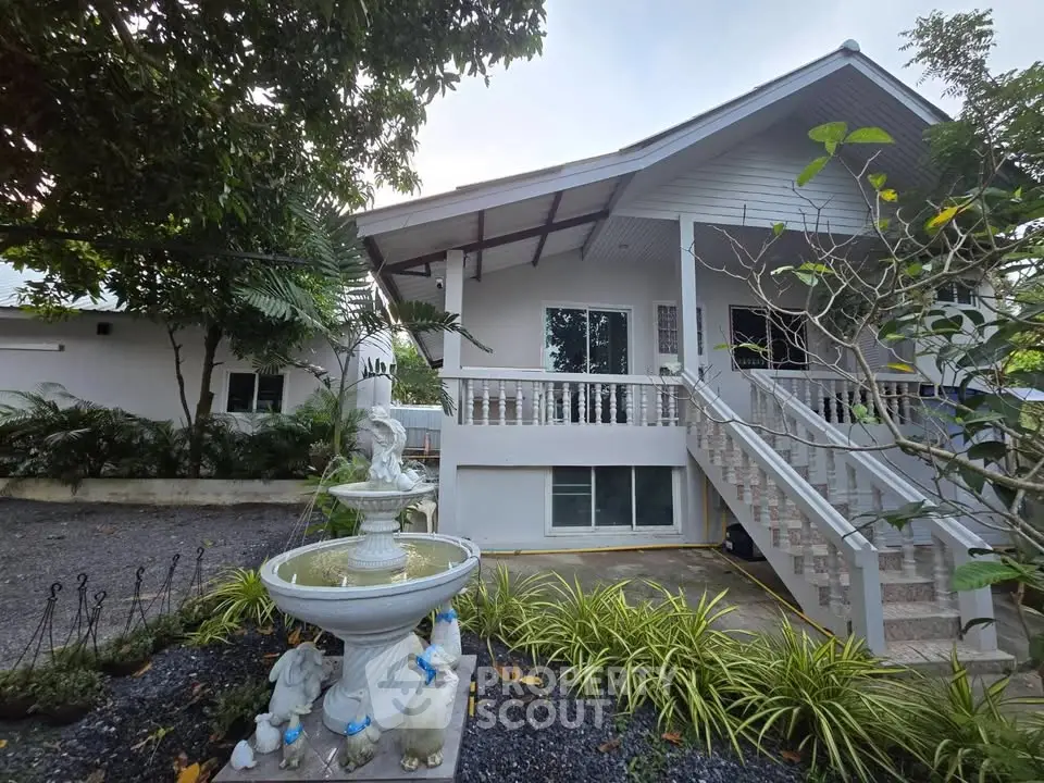 Charming white house with lush garden and decorative fountain, perfect for serene living.