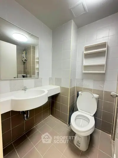 Modern bathroom with sleek fixtures and neutral tiles, featuring a wall-mounted sink and toilet.
