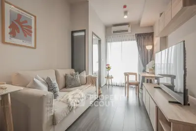 Modern living room with stylish decor and natural light, featuring a cozy sofa and sleek TV setup.