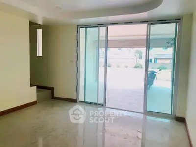 Spacious living room with sliding glass doors and polished floors, offering a bright and airy ambiance.