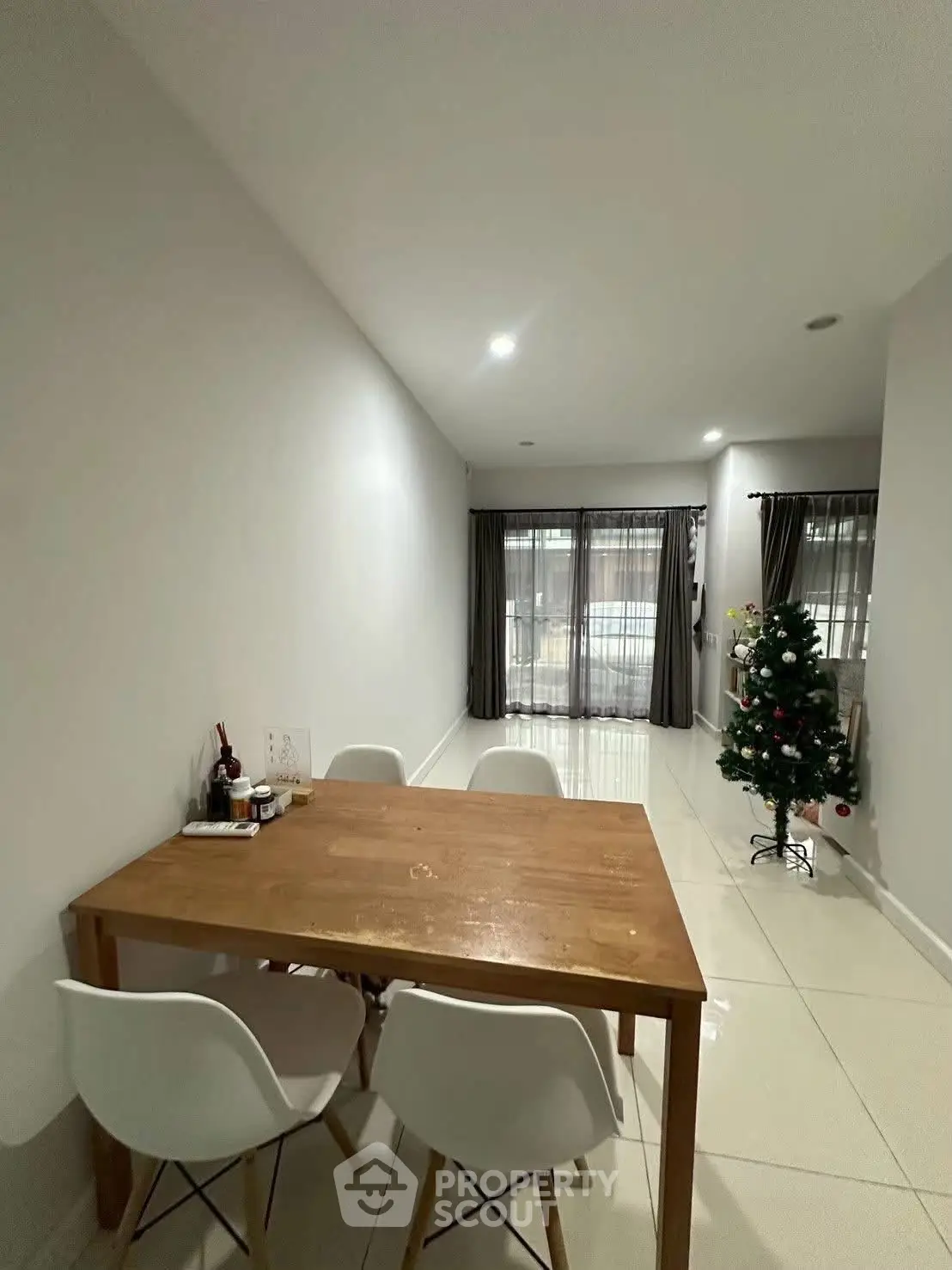 Modern dining area with wooden table and chairs, adjacent to a cozy living space with natural light.