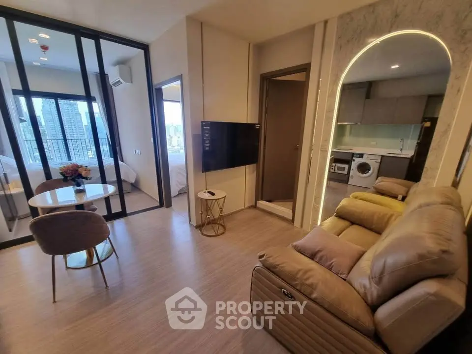 Modern living room with leather sofa, dining area, and view of kitchen and bedroom in luxury apartment.