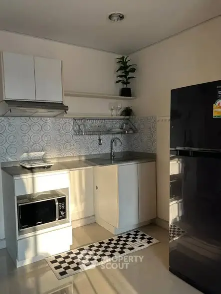 Modern kitchen with sleek appliances and stylish backsplash in cozy apartment.