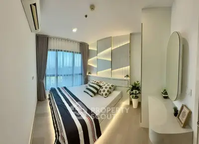 Modern bedroom with stylish decor and large window offering natural light.