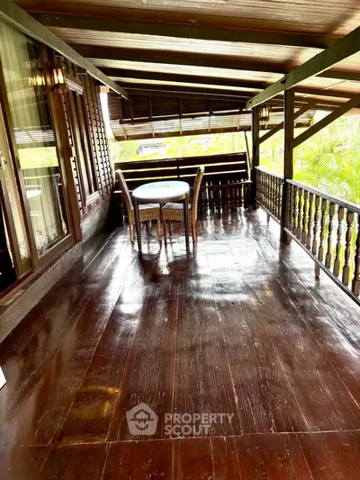 Charming wooden balcony with seating and lush greenery view, perfect for relaxation.