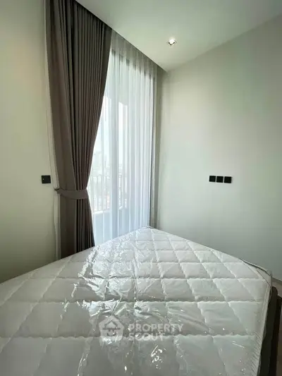 Modern bedroom with large window and elegant curtains, offering a bright and airy atmosphere.