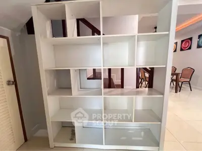 Spacious interior with modern shelving unit and dining area, perfect for stylish living.