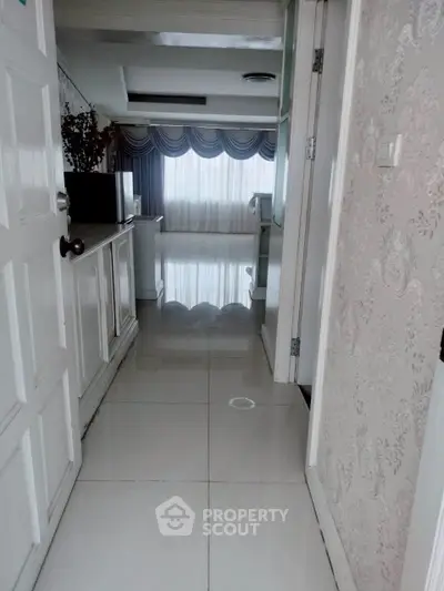 Elegant hallway leading to a bright living area with large windows and stylish decor.