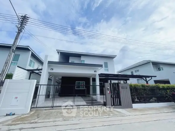 Modern two-story house with gated driveway and contemporary design in suburban neighborhood.