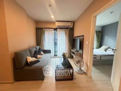 Modern living room with cozy sofa, glass coffee table, and view into a stylish bedroom.