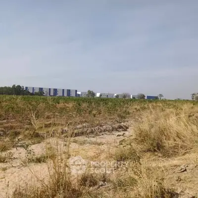 Expansive land with distant modern building under clear sky