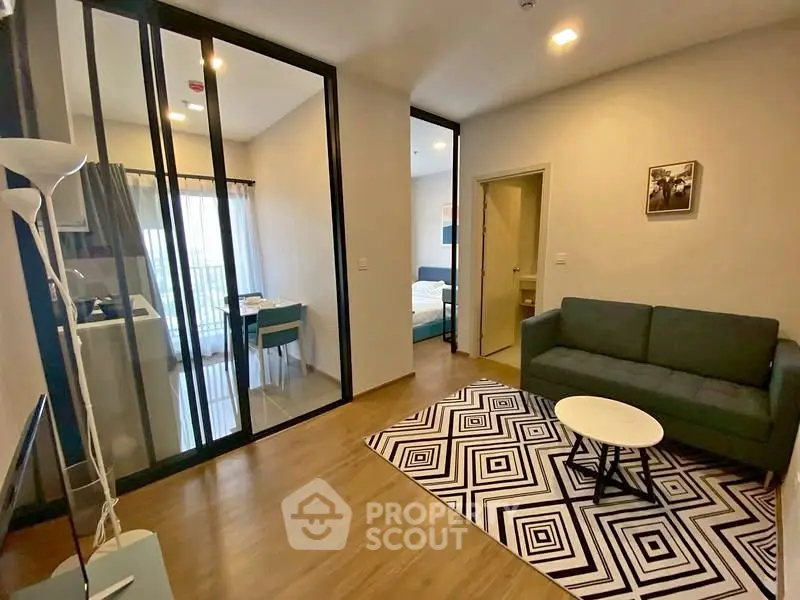 Modern living room with stylish decor and open layout, featuring a cozy sofa and geometric rug.