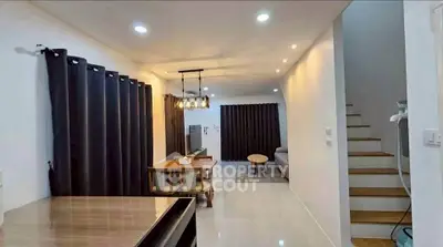 Modern living room with dining area and staircase, featuring elegant lighting and contemporary decor.