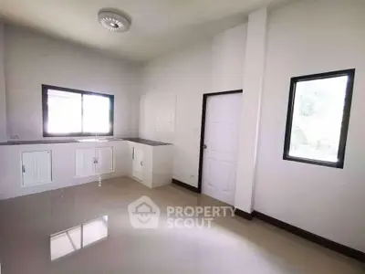 Spacious minimalist kitchen with sleek white cabinetry and ample natural light.