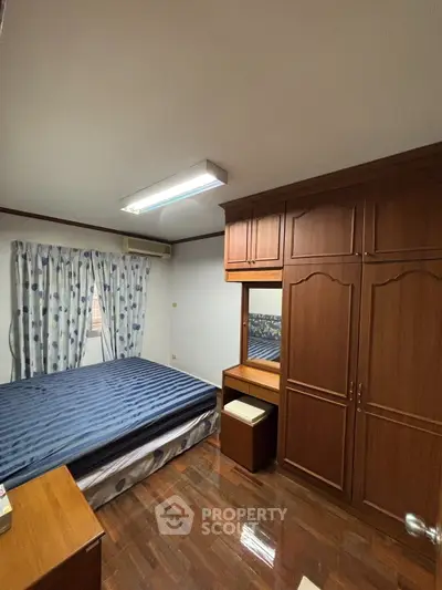 Spacious bedroom with wooden furniture and large window for natural light
