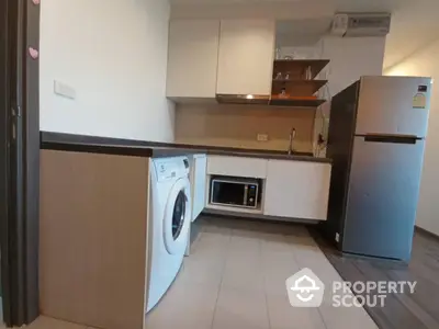 Modern kitchen with washing machine, microwave, and fridge in sleek design