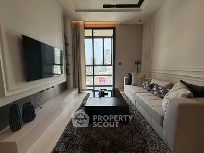 Modern living room with large TV, stylish decor, and city view through floor-to-ceiling windows.