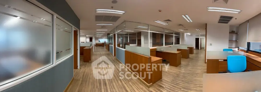 Modern office space with wooden flooring and glass partitions, ideal for a productive work environment.