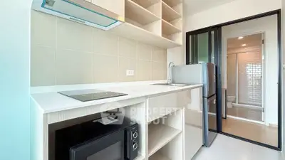Modern kitchen with sleek appliances and open shelving in a bright apartment.