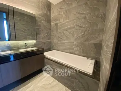 Luxurious modern bathroom with elegant marble tiles and sleek bathtub design.