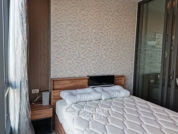 Modern bedroom with elegant textured wall and large windows for natural light.