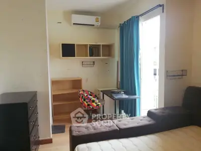 Cozy bedroom with study area, featuring a colorful chair, air conditioning, and natural light from a large window.