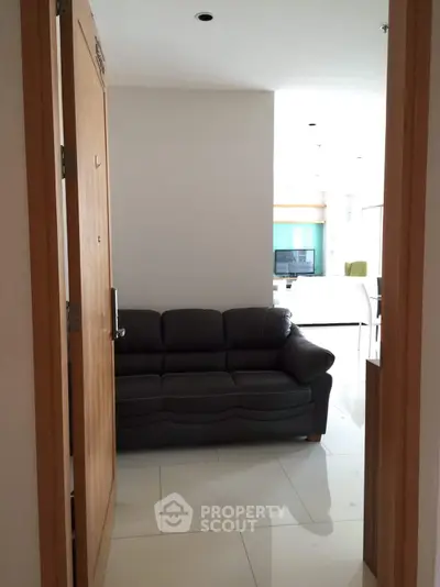 Modern apartment entrance with cozy leather sofa and bright interior lighting.