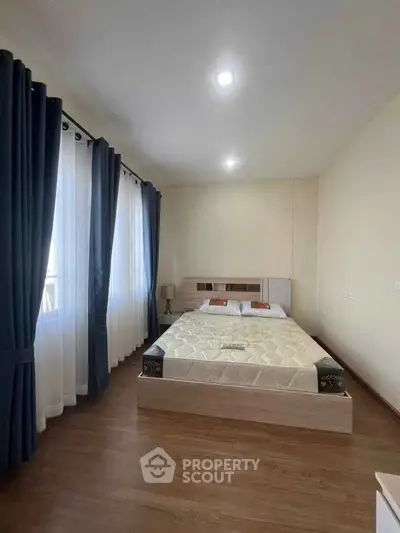 Spacious bedroom with large windows and elegant curtains, perfect for natural light lovers.