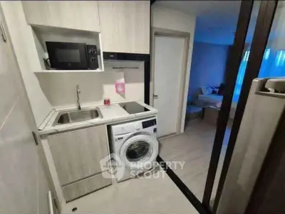 Compact modern kitchen with washing machine and microwave in cozy apartment.