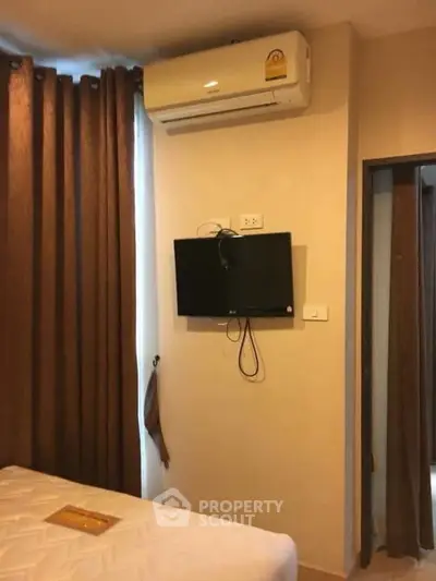 Cozy bedroom with air conditioning and wall-mounted TV, perfect for modern living.