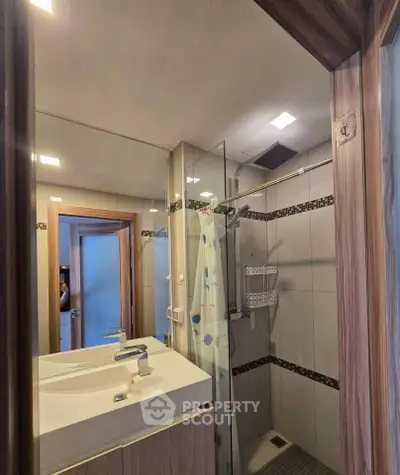 Modern bathroom with sleek fixtures and glass shower enclosure in a stylish apartment.