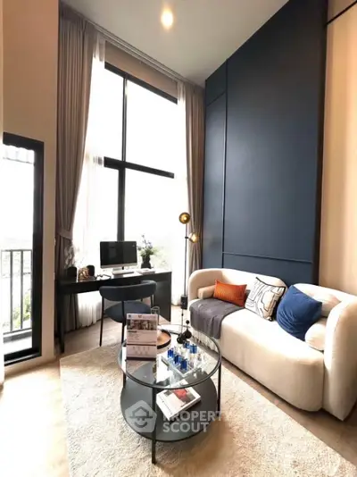 Modern living room with high ceilings and large windows, featuring stylish furniture and decor.