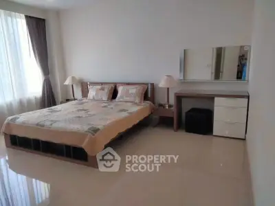 Spacious bedroom with large window and modern furnishings in a bright apartment.