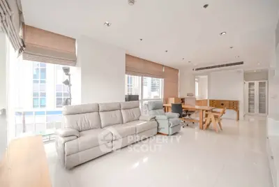 Spacious modern living room with white leather sofa and large windows in a high-rise apartment.