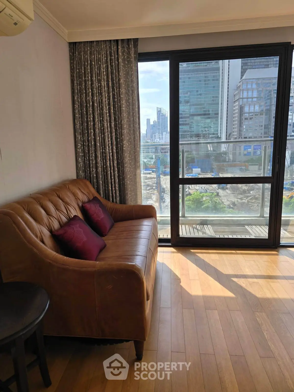 Stylish living room with leather sofa and city view from large window, perfect urban retreat.