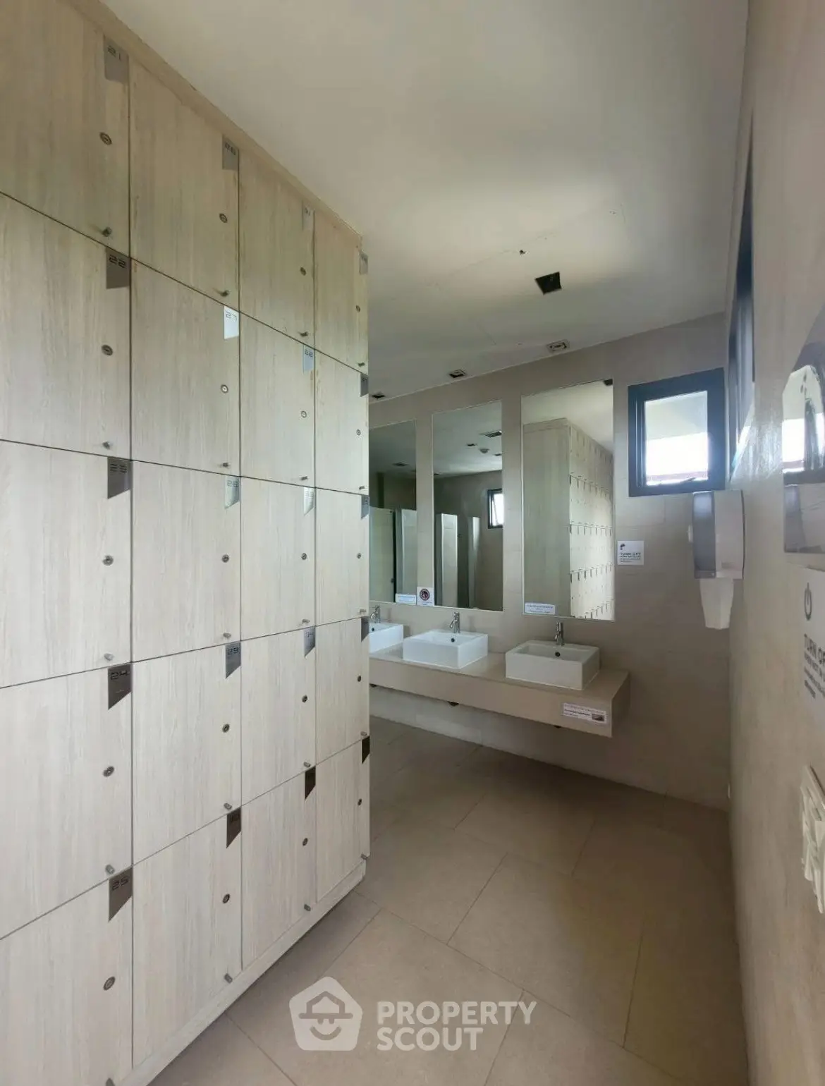 Modern communal bathroom with sleek lockers and stylish sinks in a contemporary building.