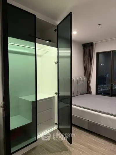 Modern bedroom with glass wardrobe and city view, perfect for urban living.