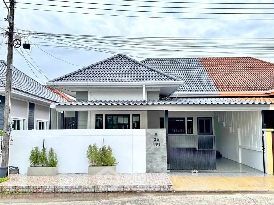 Charming single-story house with modern roof design and spacious driveway.