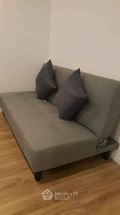 Cozy gray sofa with cushions on wooden floor in modern living room corner.