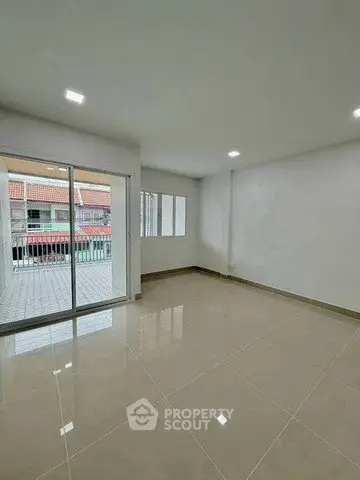 Spacious empty living room with glossy tiled floor and large windows leading to a balcony.