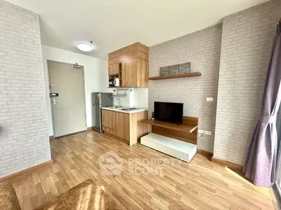 Modern studio apartment with compact kitchen and cozy living area, featuring wood flooring and natural light.