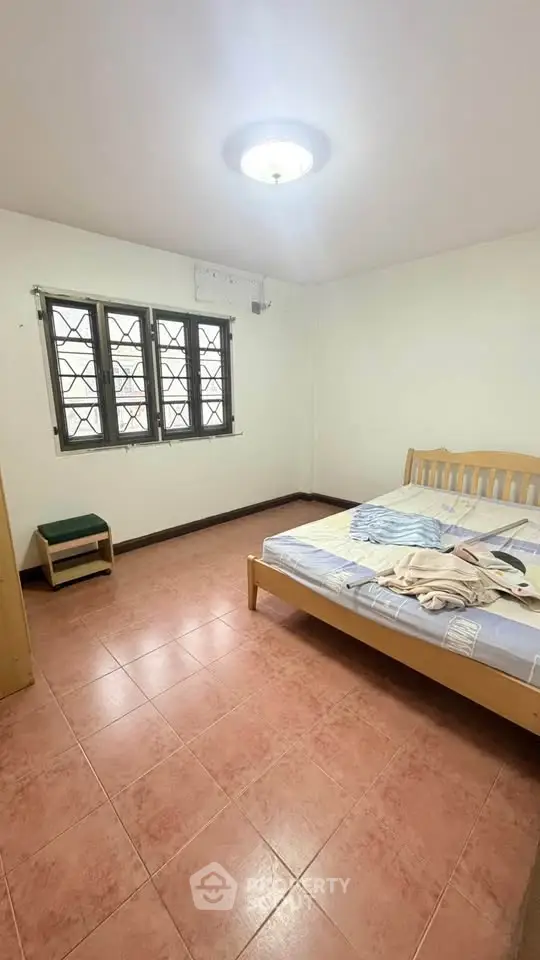 Spacious bedroom with natural light and tiled flooring in a cozy home.