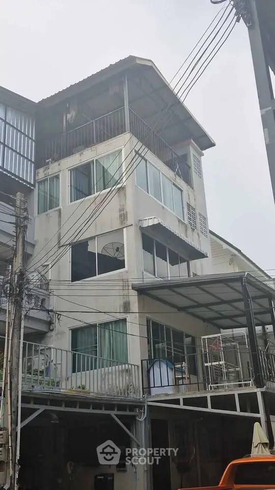 Urban multi-story building with balconies and rooftop in a bustling neighborhood.