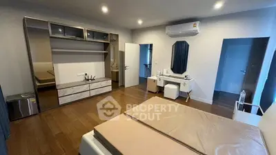 Spacious modern bedroom with wooden flooring and built-in wardrobe
